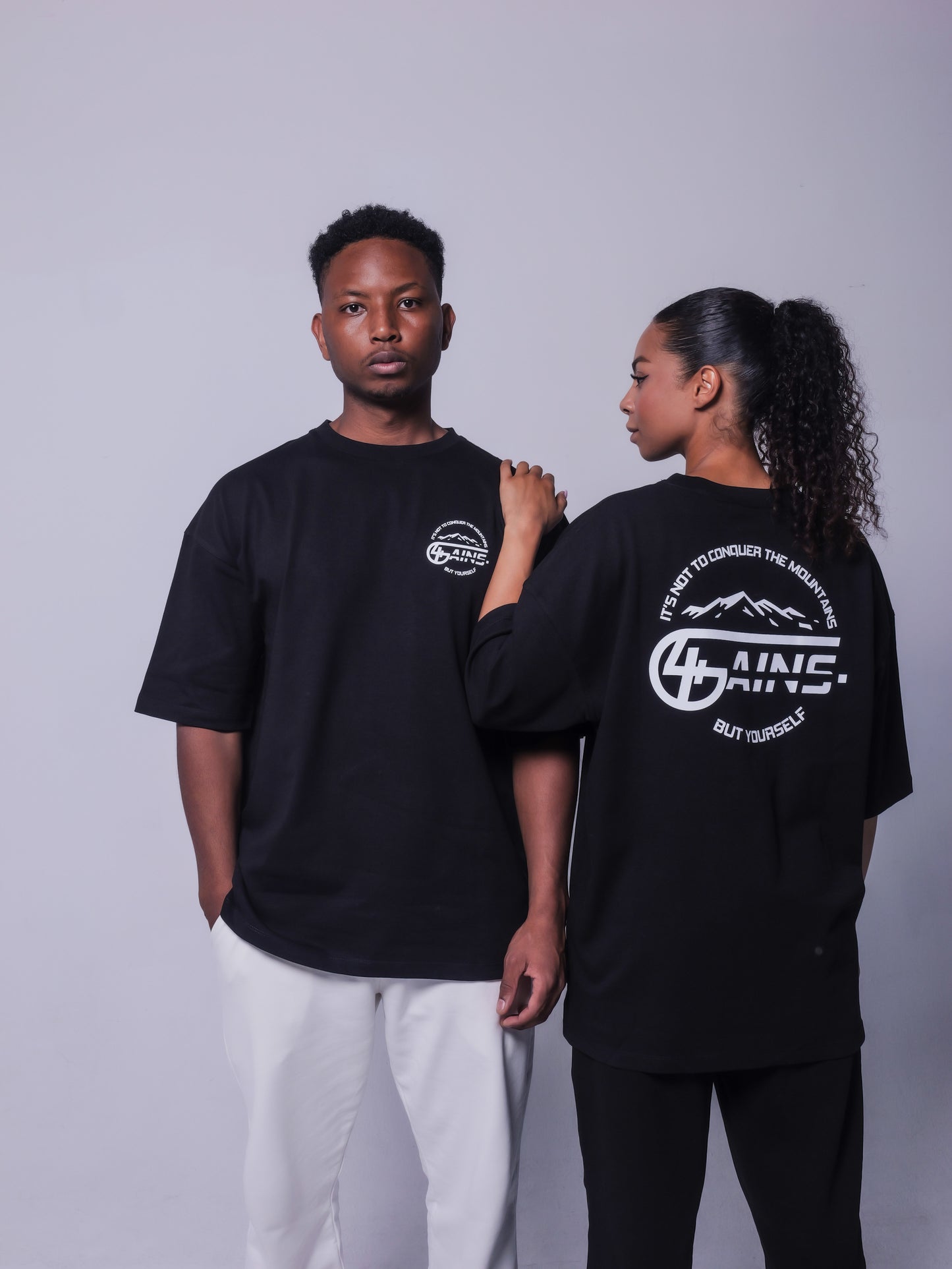 Schwarzes 4GAINS Mountains T-Shirt mit oversized Schnitt an einem weiblichen und männlichen Model