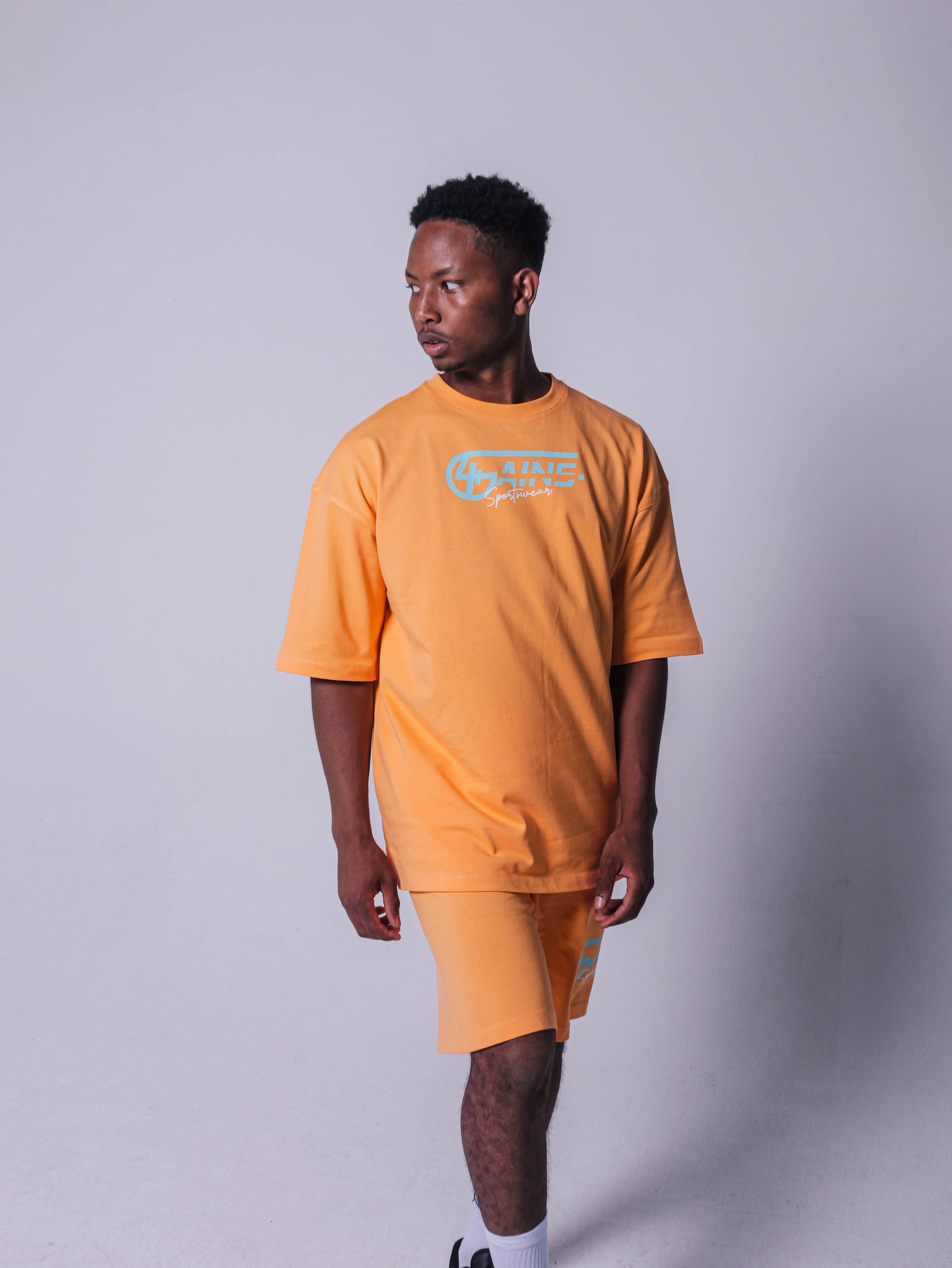 4GAINS Sportswear oversized T-shirt in der Farbe apricot mit türkisenem Aufdruck an einem männlichen Model