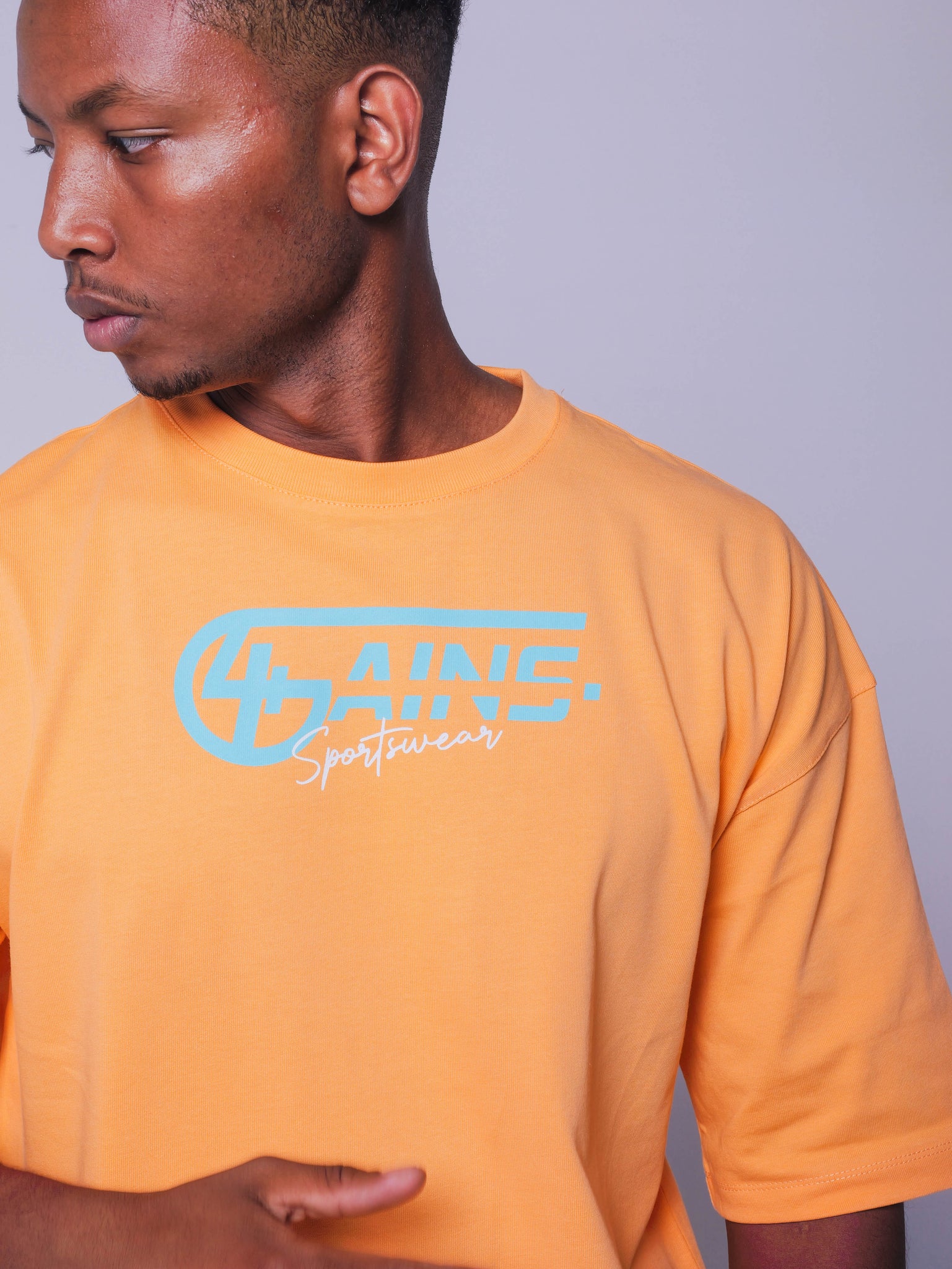 4GAINS Sportswear oversized T-shirt in der Farbe apricot mit türkisenem Aufdruck an einem männlichen Model