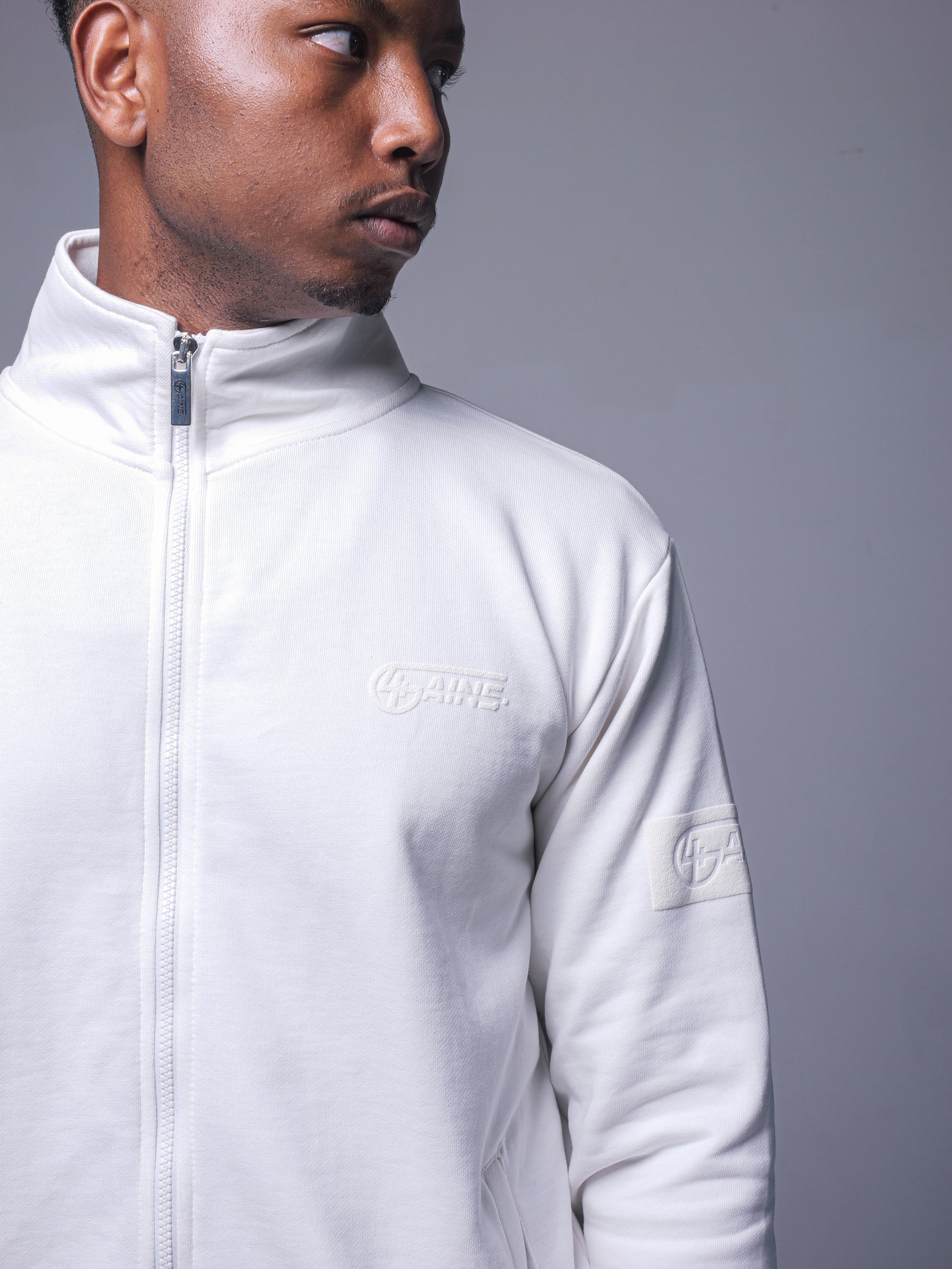 4GAINS Tracksuit Jacke in der Farbe Cream mit Creamfarbenem Puff Print an einem stehenden männlichem Model