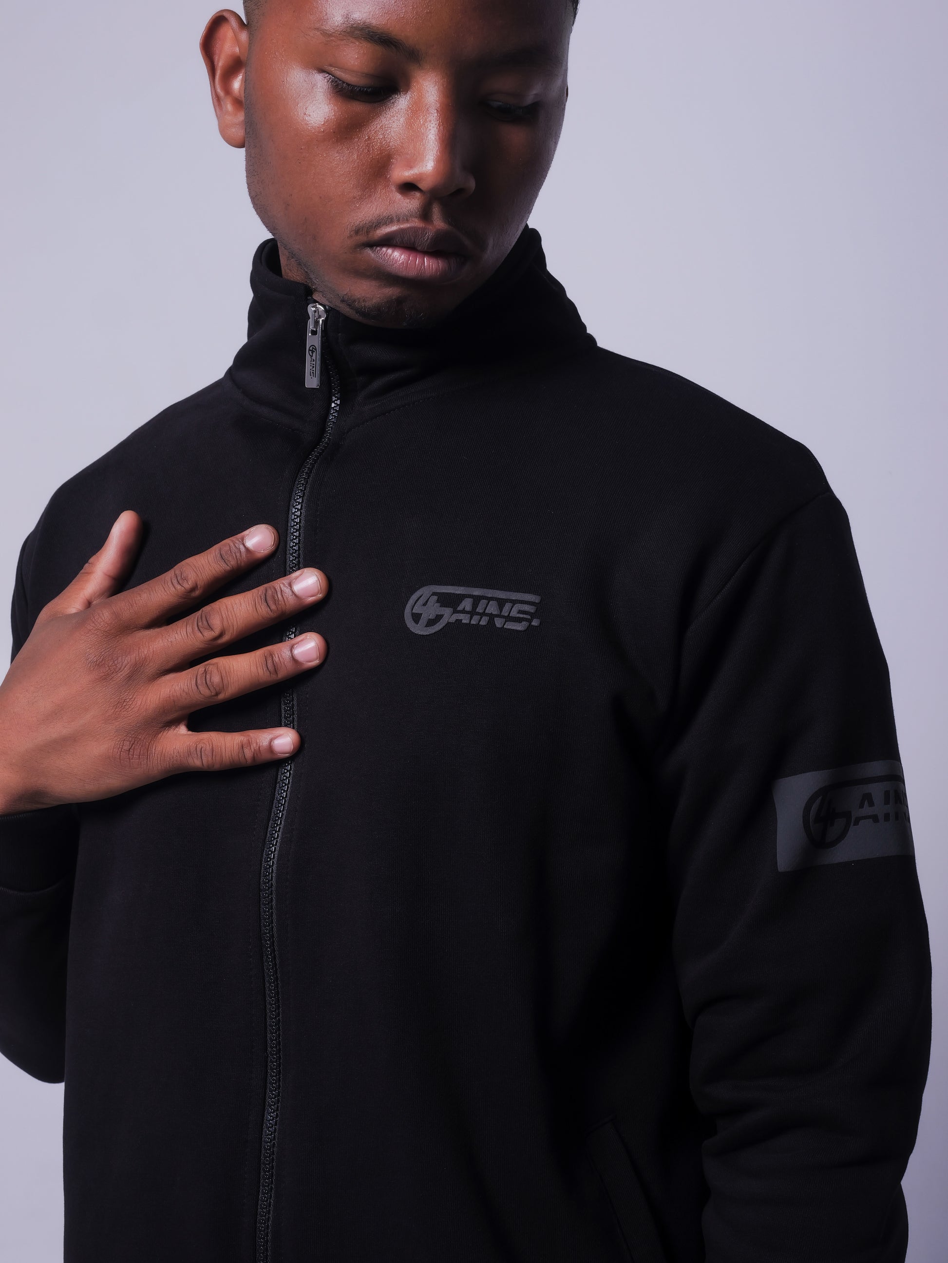 4GAINS Tracksuit Jacke in der Farbe schwarz mit schwarzem Puff Print an einem männlichem Model 