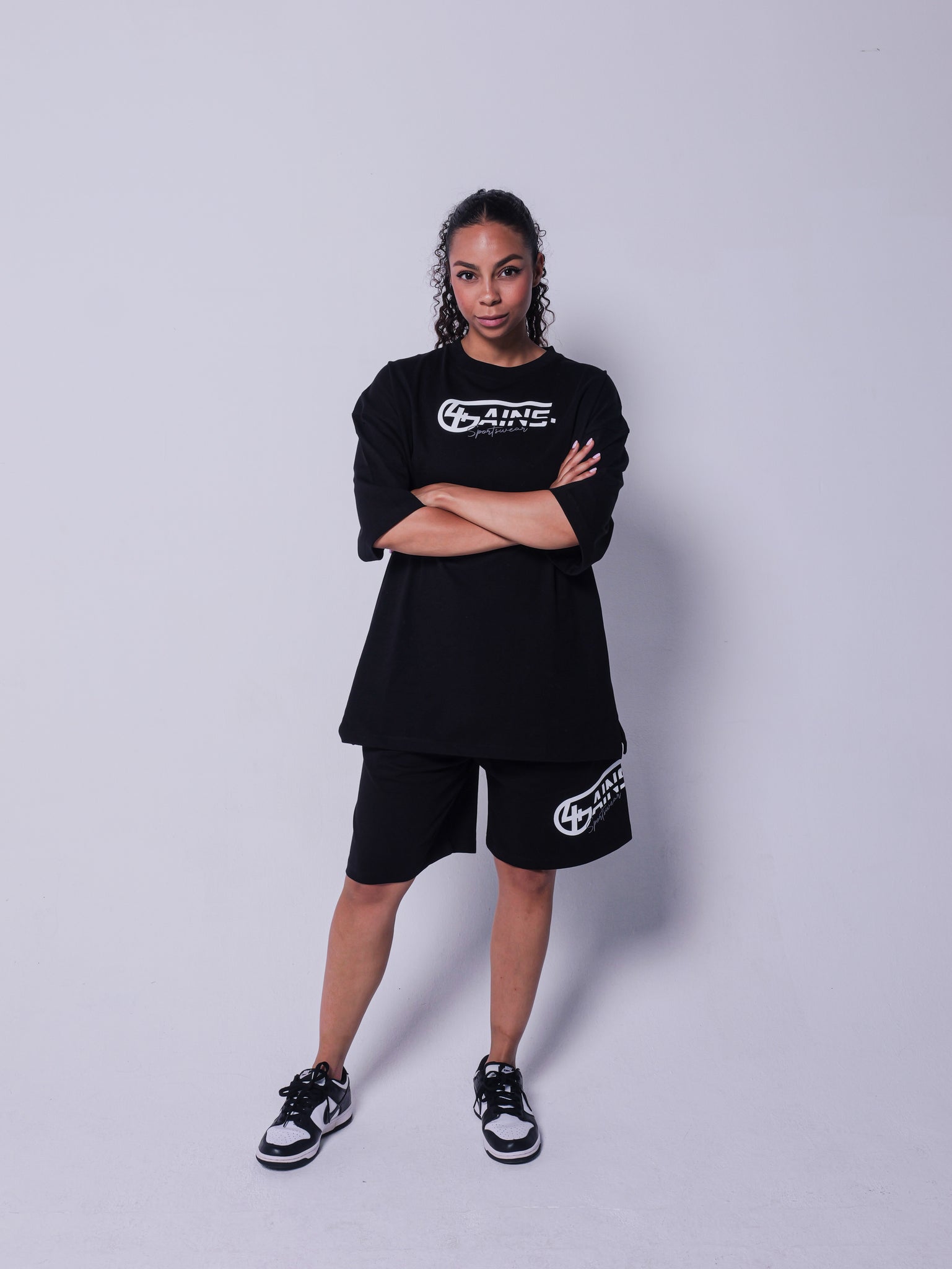 4GAINS Sportswear kurze Hose in der Farbe schwarz mit weißem Aufdruck an einem weiblichen stehenden Model 