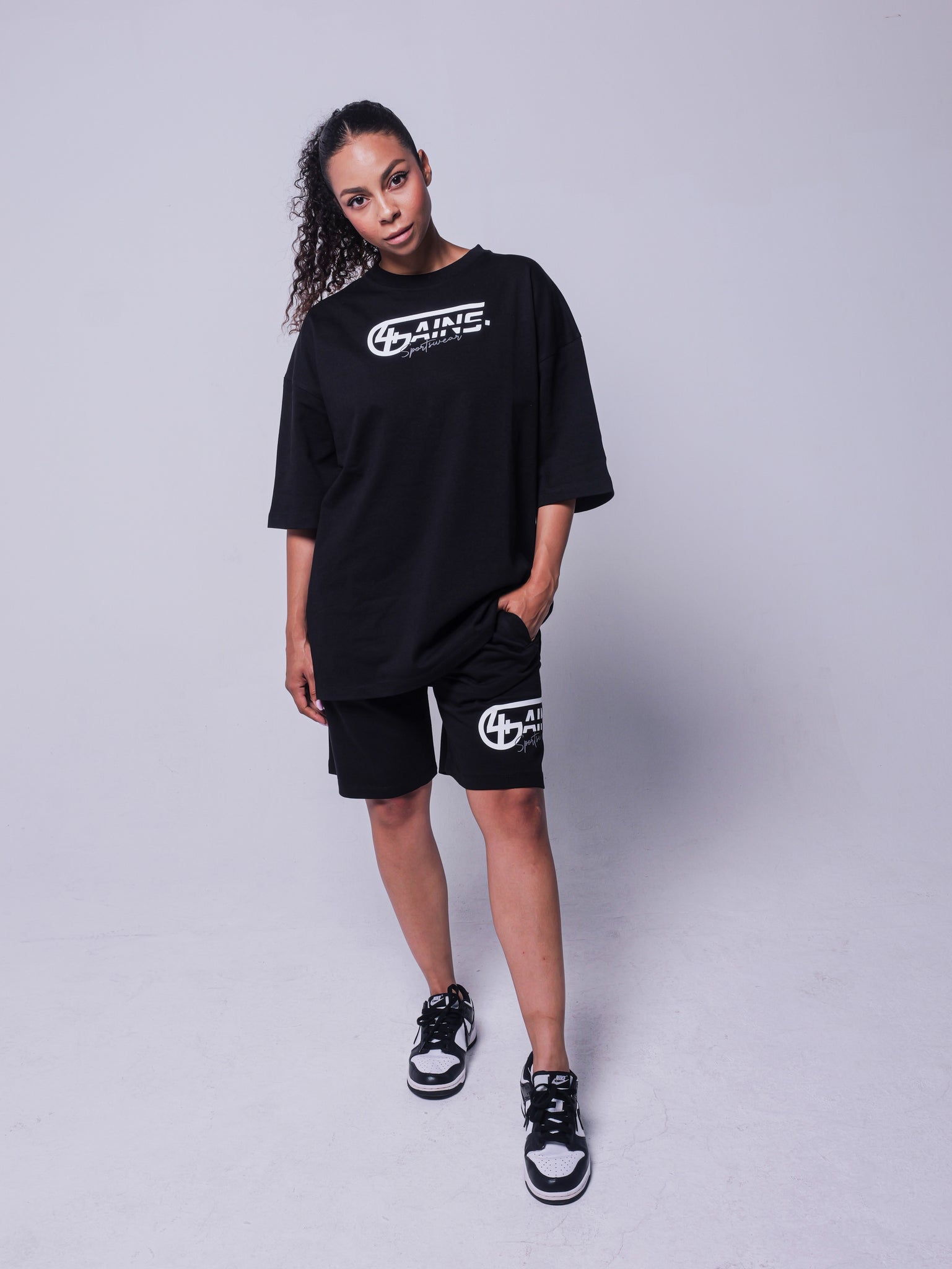 4GAINS Sportswear oversized T-shirt in der Farbe schwarz mit weißem Aufdruck an einem weiblichem Model stehend
