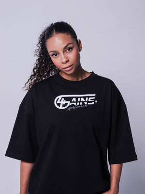 4GAINS Sportswear oversized T-shirt in der Farbe schwarz mit weißem Aufdruck an einem weiblichen Model stehend