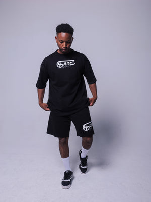 4GAINS Sportswear oversized T-shirt in der Farbe schwarz mit weißem Aufdruck an einem männlichem Model stehend