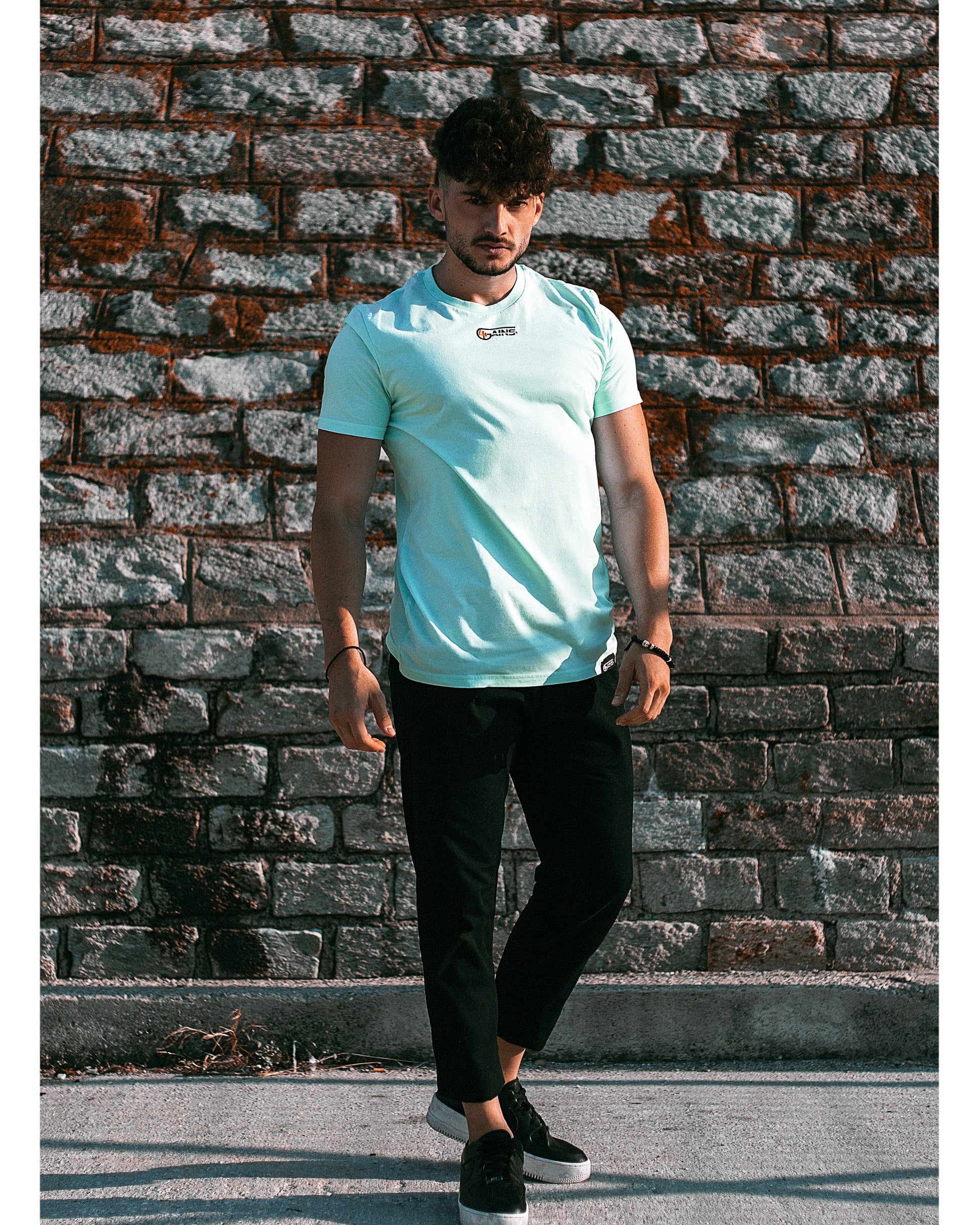 Model trägt 4GAINS unisex T-Shirt in light blue/black/orange