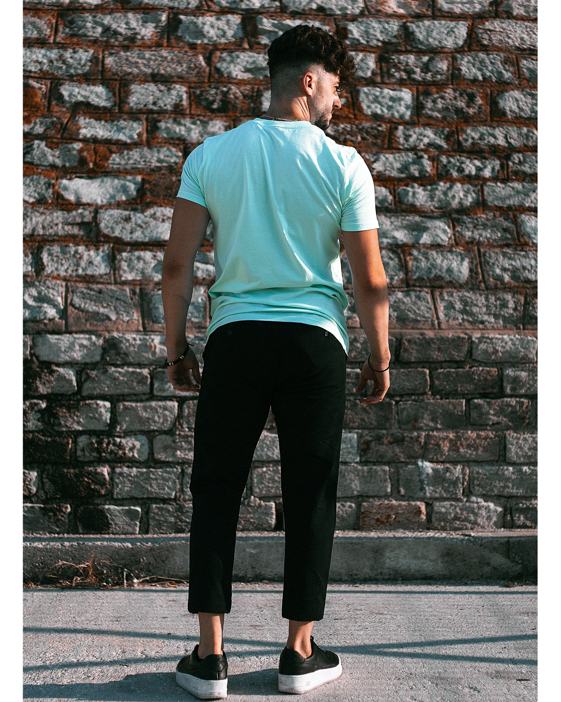 Model trägt 4GAINS unisex T-Shirt in light blue/black/orange