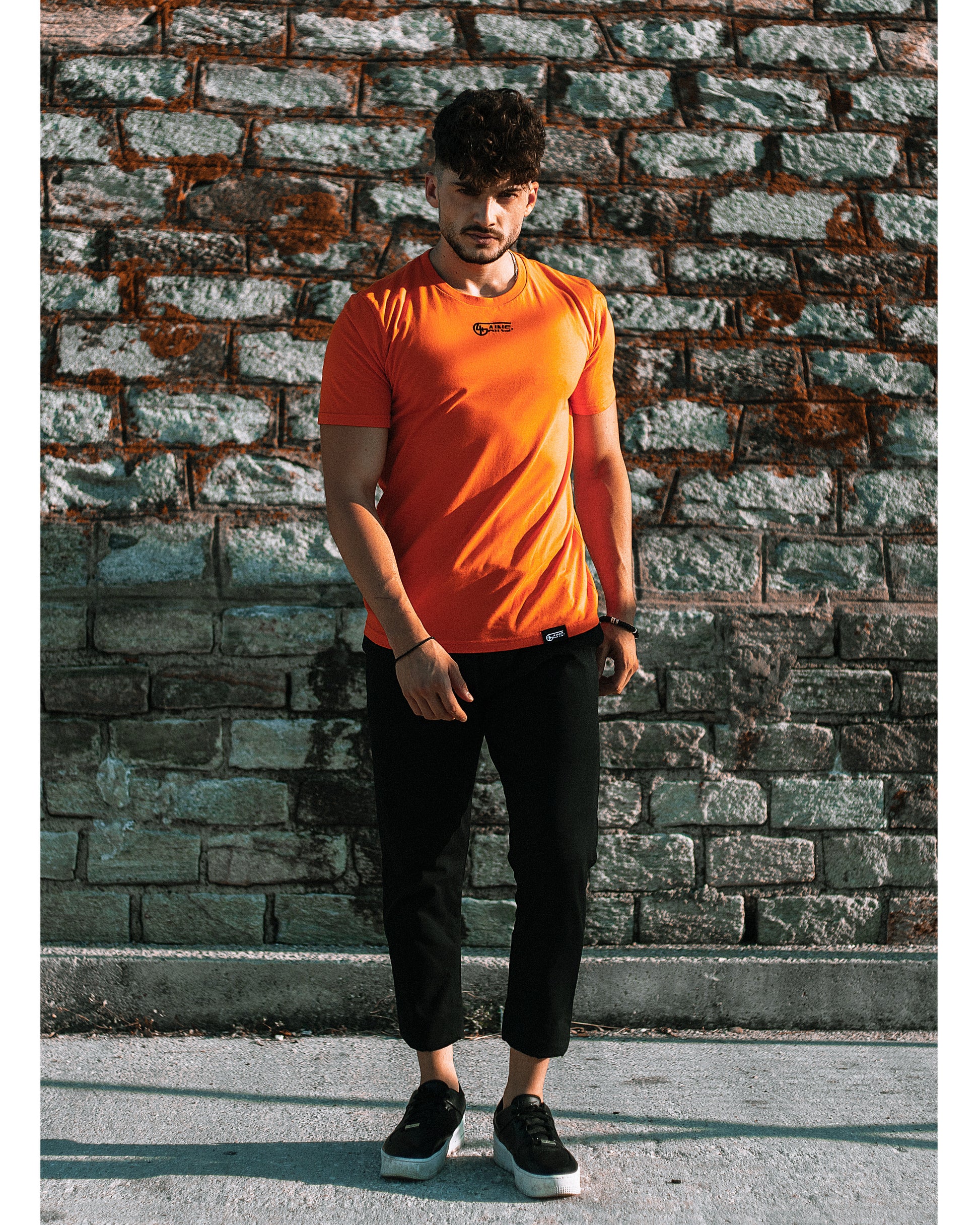Model trägt 4GAINS unisex T-Shirt in orange/black