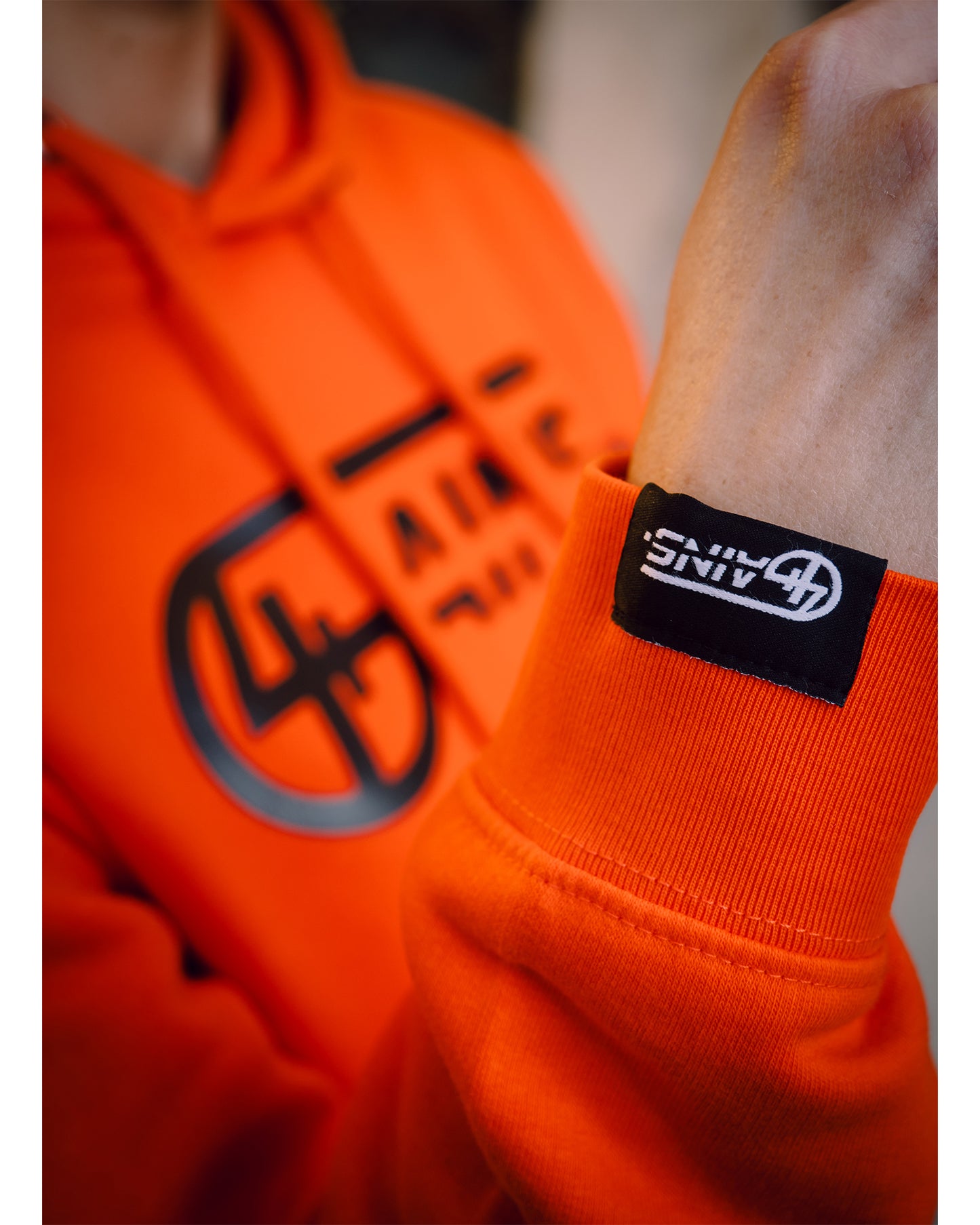 Weblabel am Arm vom 4GAINS orange/black Hoodie