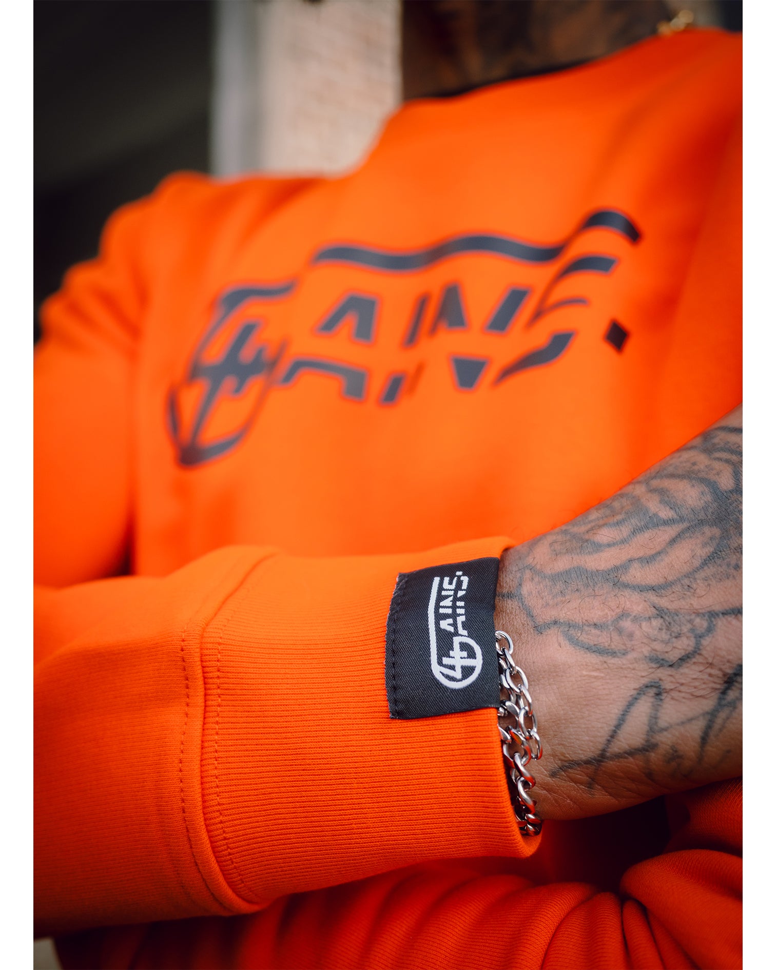 Weblabel am Arm vom unisex 4GAINS orange/black Sweater 